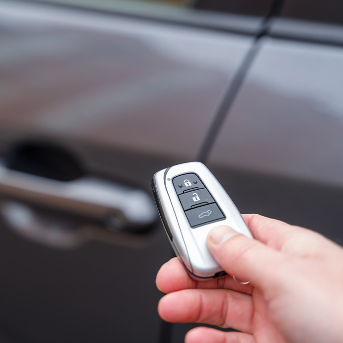 Hand holding car key remote control, unlocking vehicle